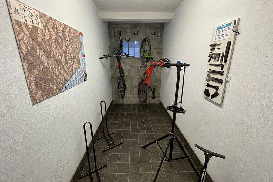 Bike room privata con rastrelliere, ganci, mappa e banco per la manutenzione