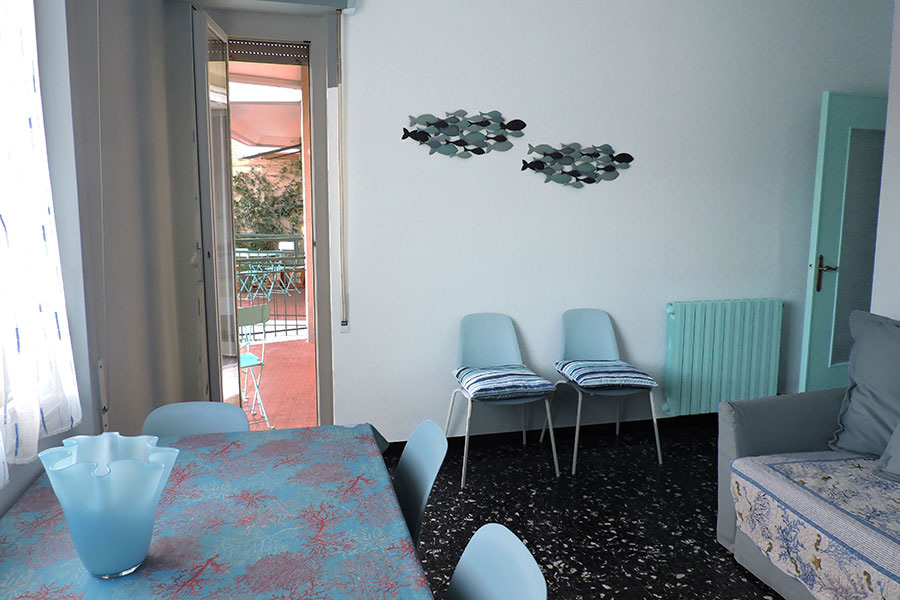 Soggiorno con tavolo da pranzo e portafinestra verso il balcone
