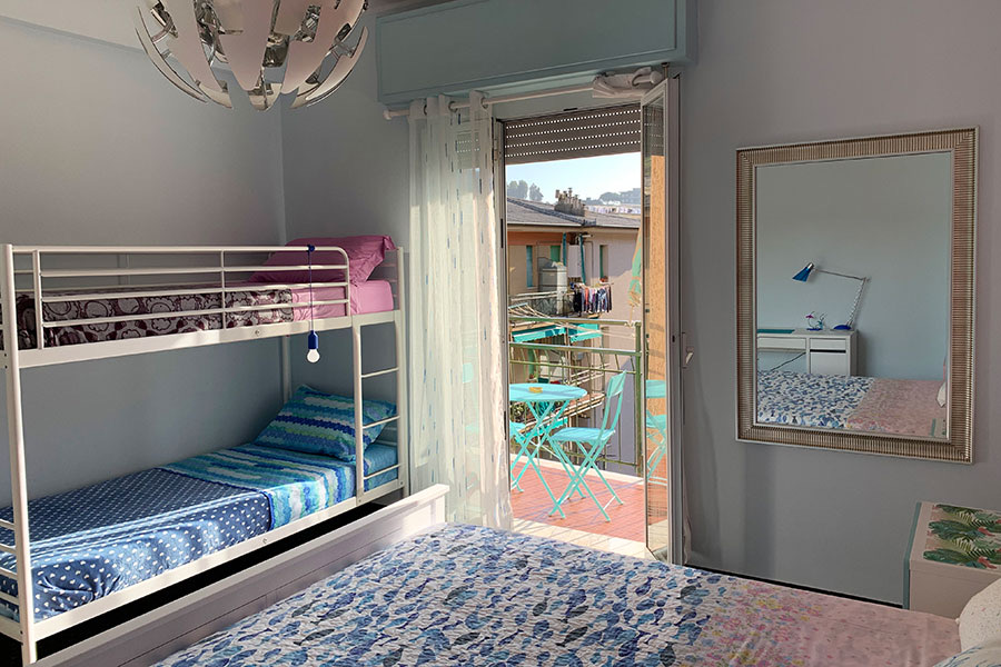 Camera con letto matrimoniale, letto a castello e portafinestra sul balcone